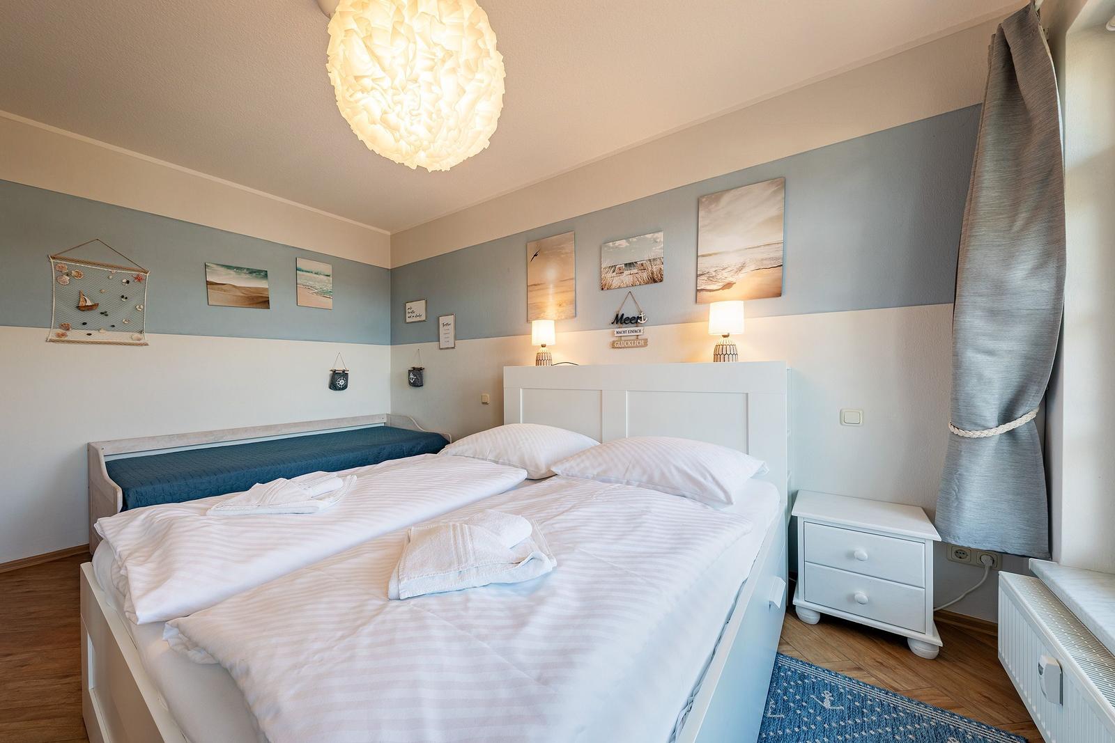Schlafzimmer mit Doppelbett, Wandbildern und Nachttisch