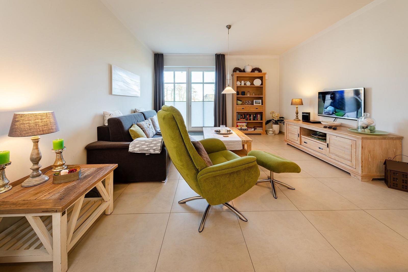 Wohnzimmer mit grüner Sessel, Sofa und Fernseher.