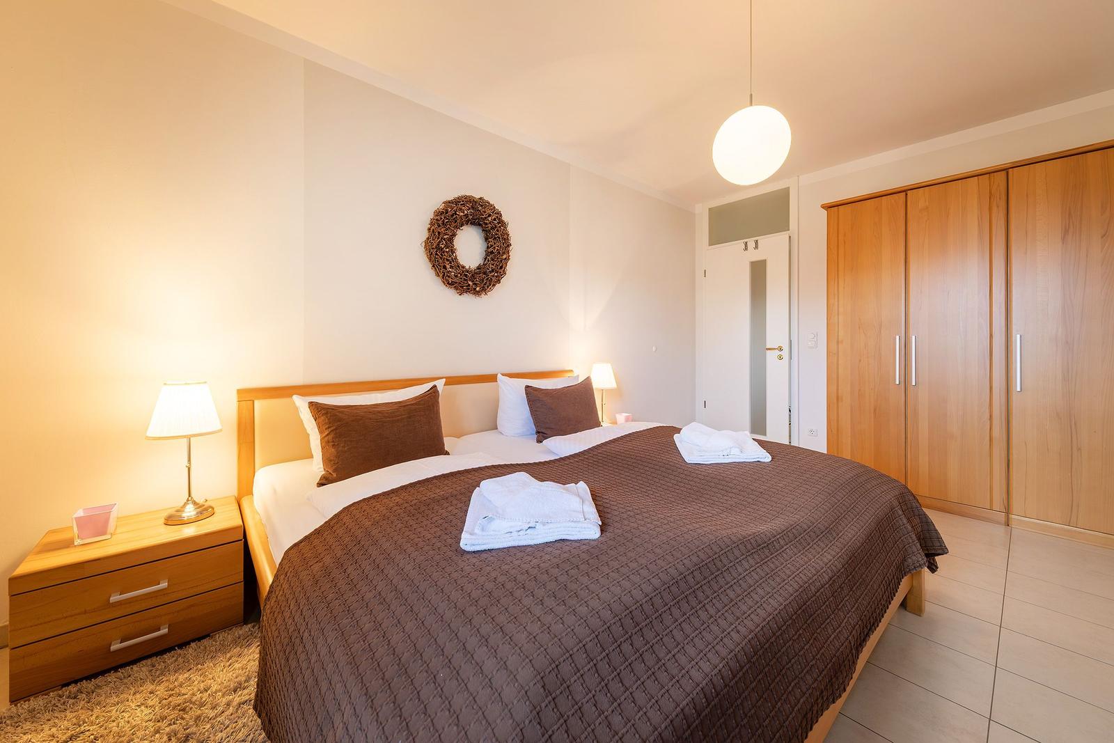 Schlafzimmer mit Doppelbett, Holzmöbel und Deckenventilator.