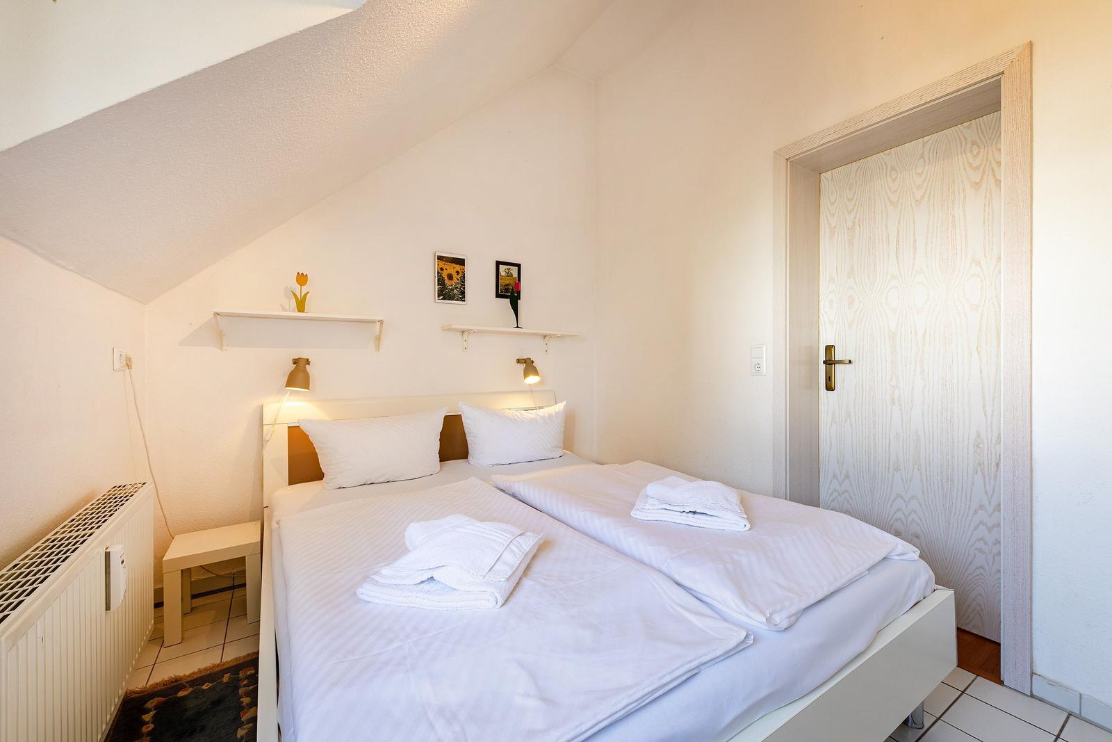 Ein Schlafzimmer mit Doppelbett, zwei Nachttischen und einer Tür.