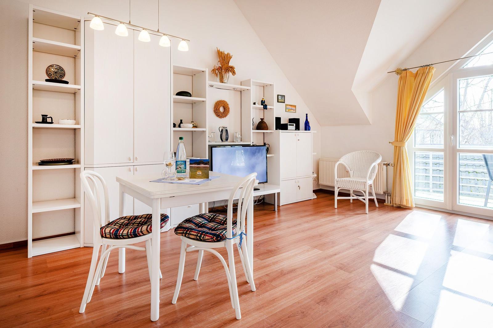 Ein Esszimmer mit Tisch, Stühlen und integrierten Schränken unter schrägem Dach.
