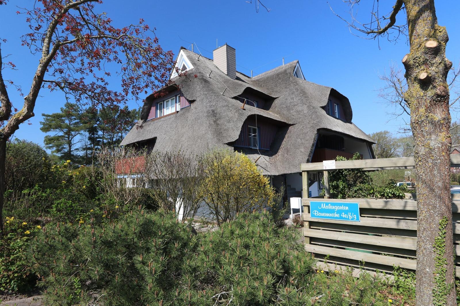 Dorfhaus mit Strohdach und Holzveranda im Garten