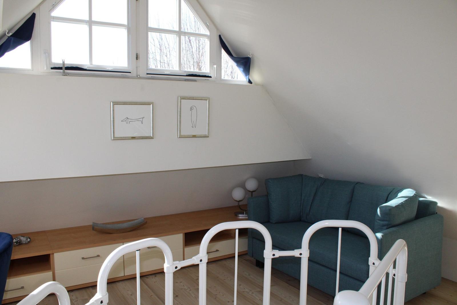 Ein Raum mit einem Sofa, einem Schrank und zwei Bildern an der Wand.