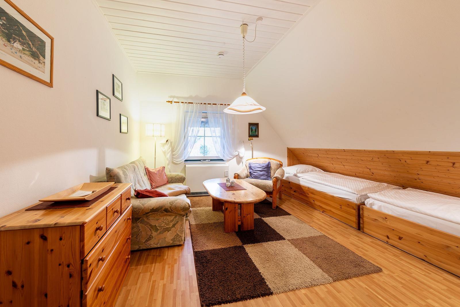 Zimmer mit zwei Betten, Sofa, Couchtisch und Holzmöbel.