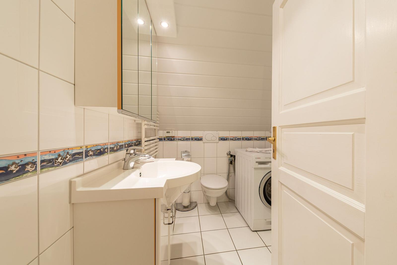 Badezimmer mit Waschmaschine, Toilette und Spiegel