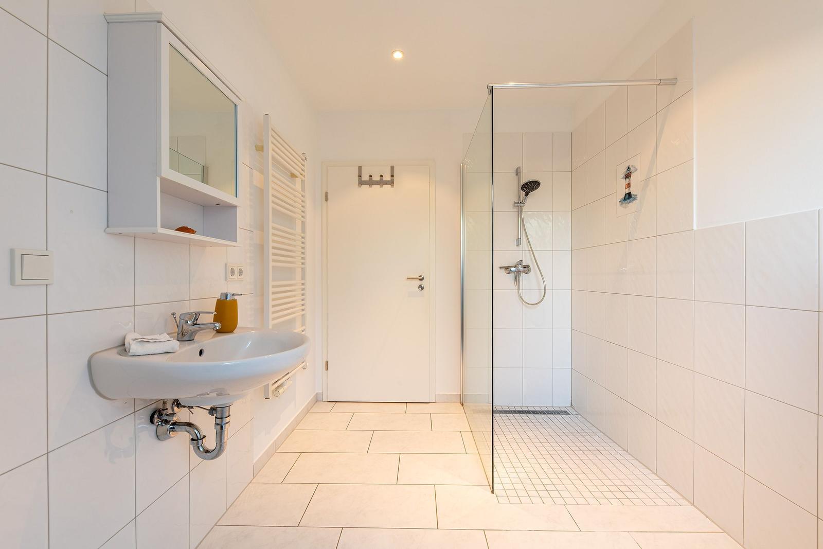 Badezimmer mit Dusche, Waschbecken und Spiegelschrank.