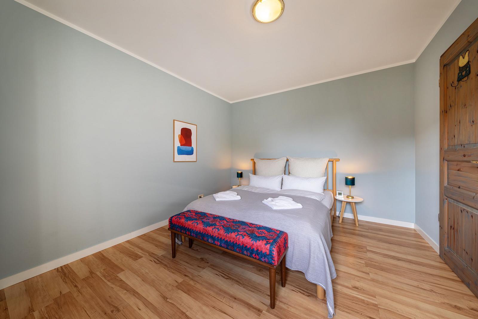 Schlafzimmer mit Bett, Holzboden und Wandbild.