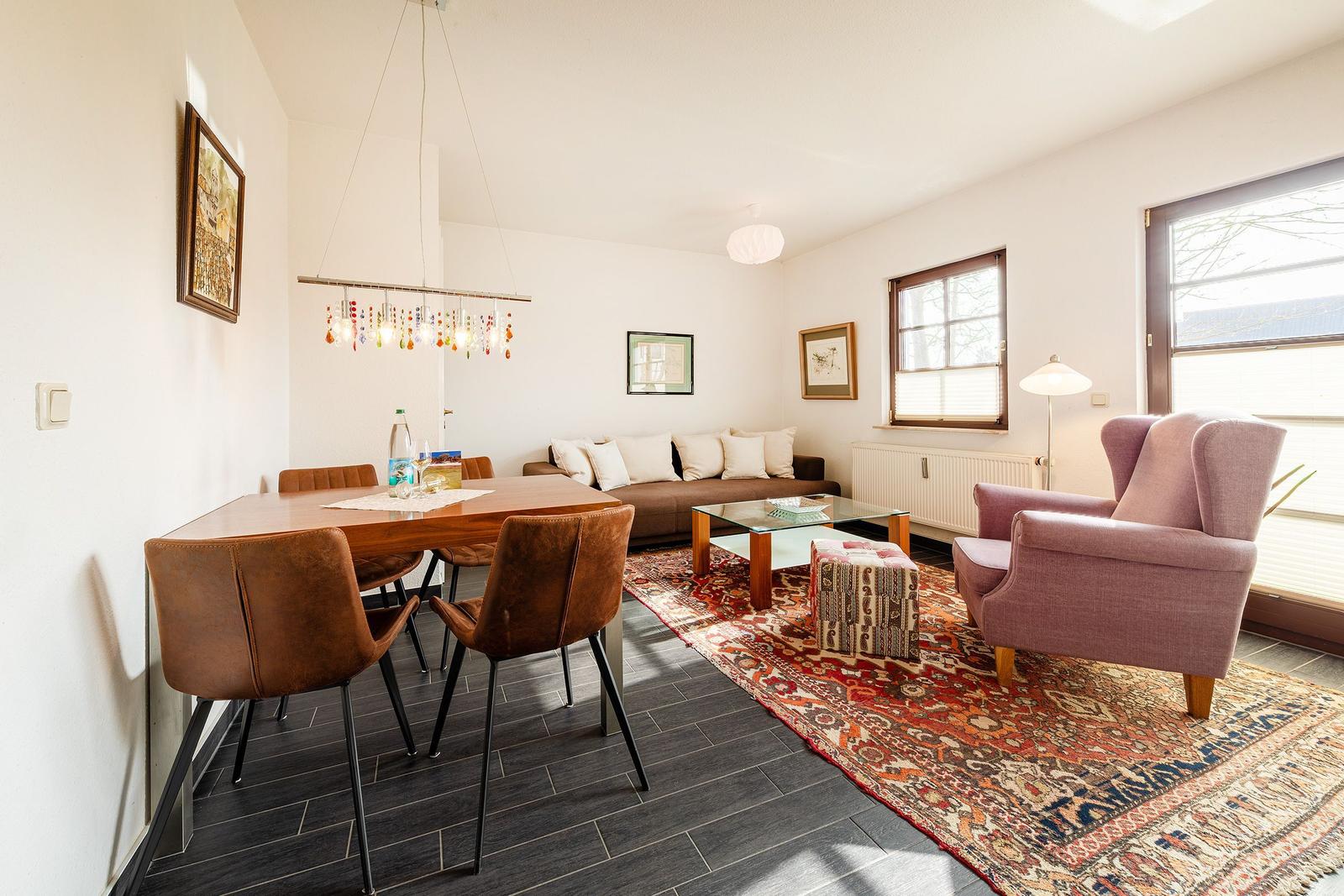Wohn- und Essbereich mit Sofa, Stühlen und Teppich.