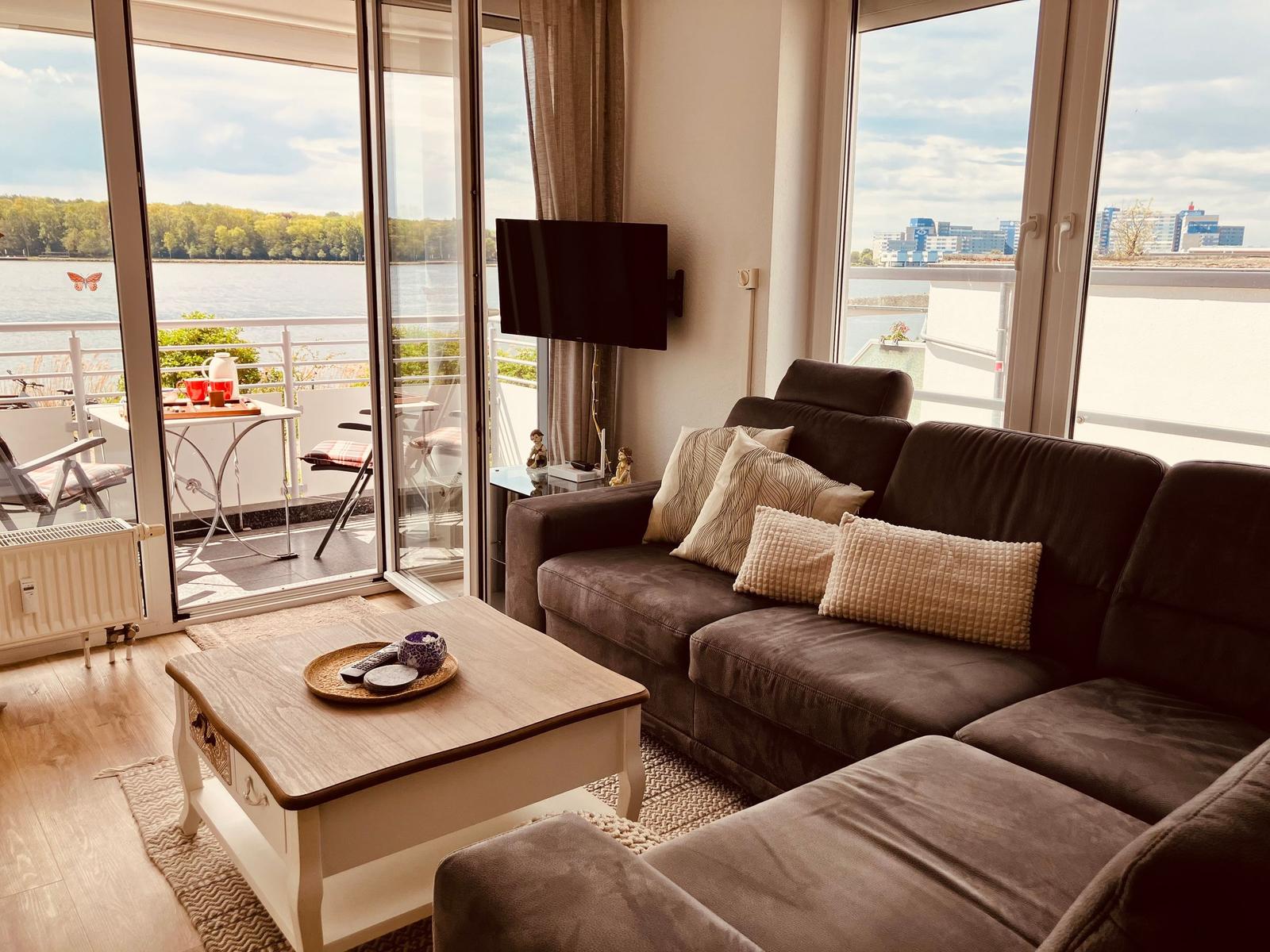 Wohnzimmer mit Sofa, Couchtisch und Blick auf Fluss und Stadt