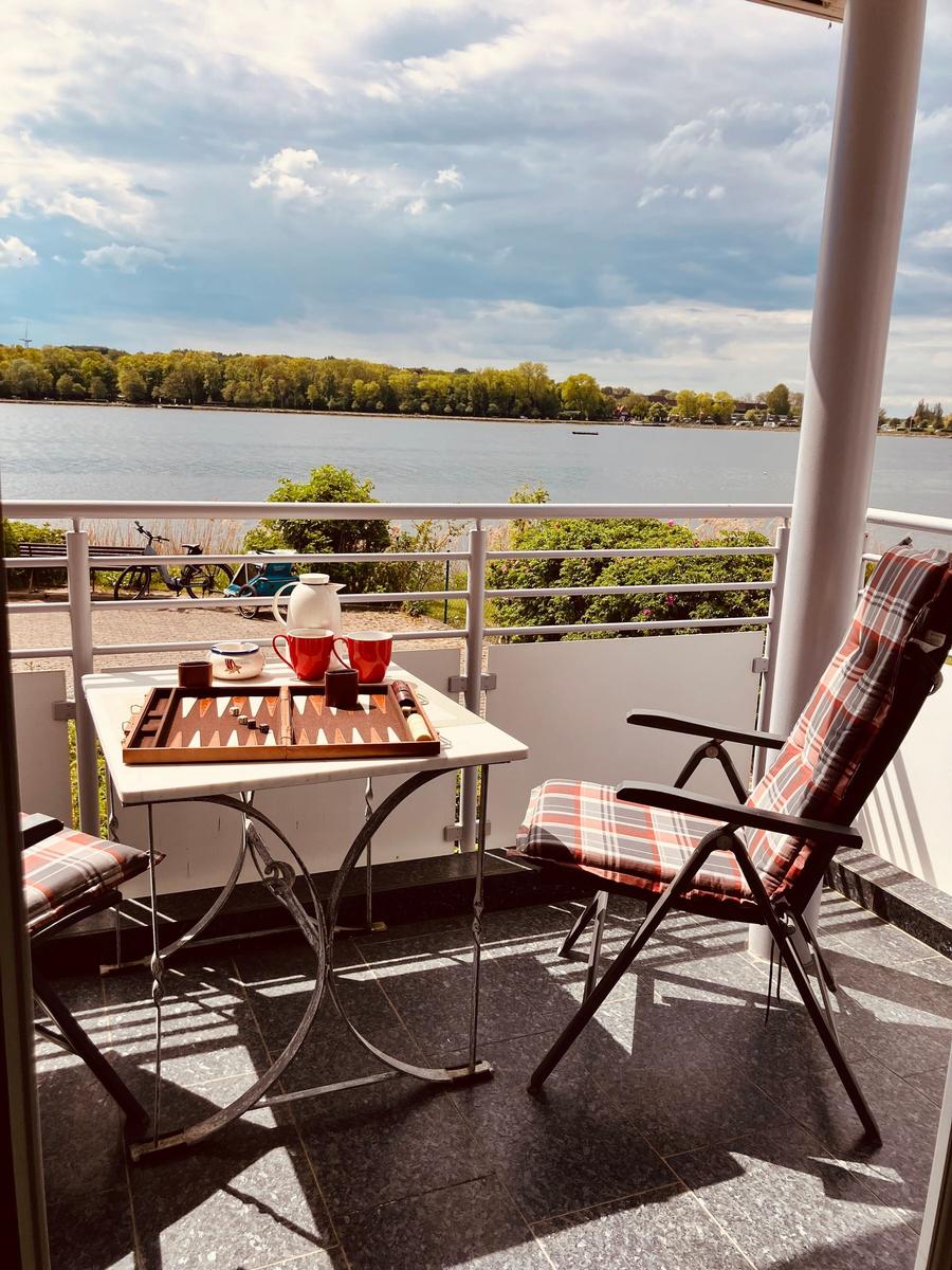 Balkon mit Tisch, Stühlen und Blick auf See
