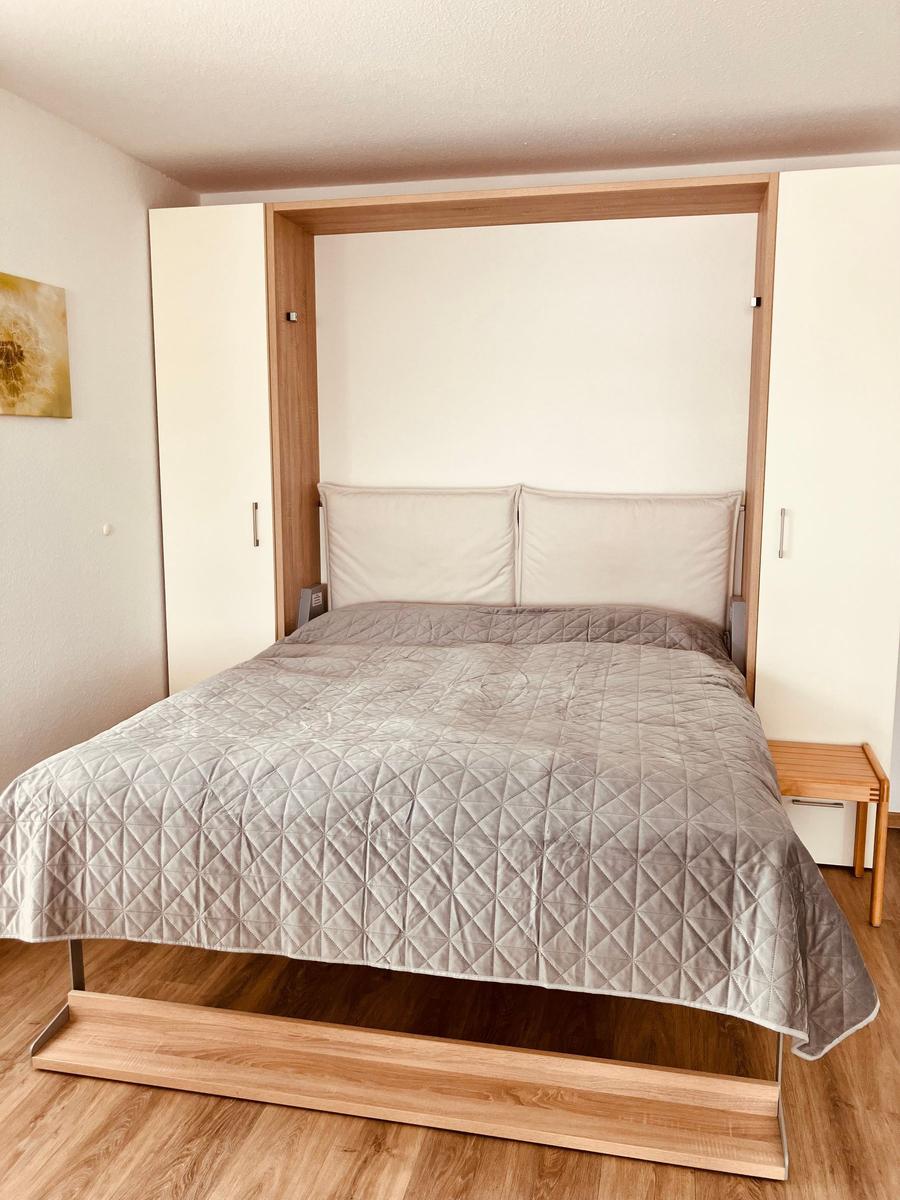 Schlafzimmer mit Bett, Holzfußboden und Wandbild.
