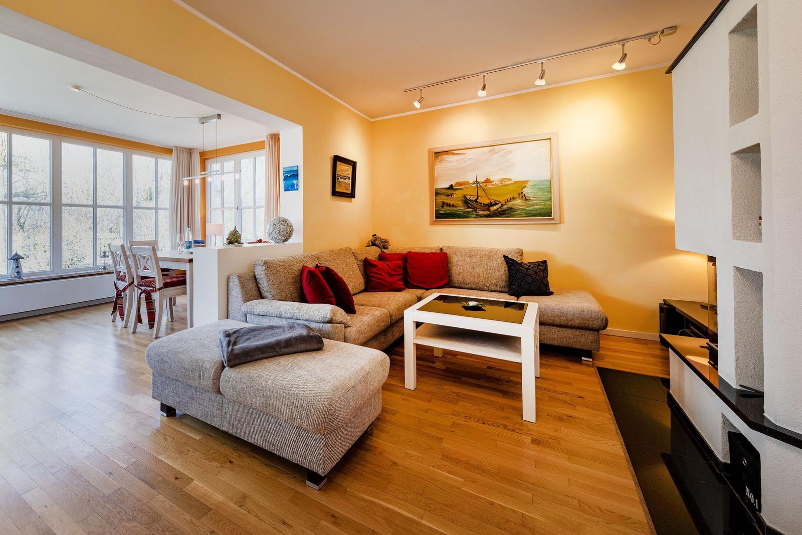 Wohnzimmer mit Sofa, Couchtisch und Essbereich. Holzboden und Wandbild sichtbar.