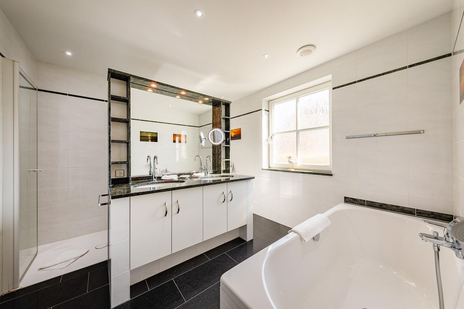Badezimmer mit Dusche, Badewanne und Waschbecken mit Spiegel