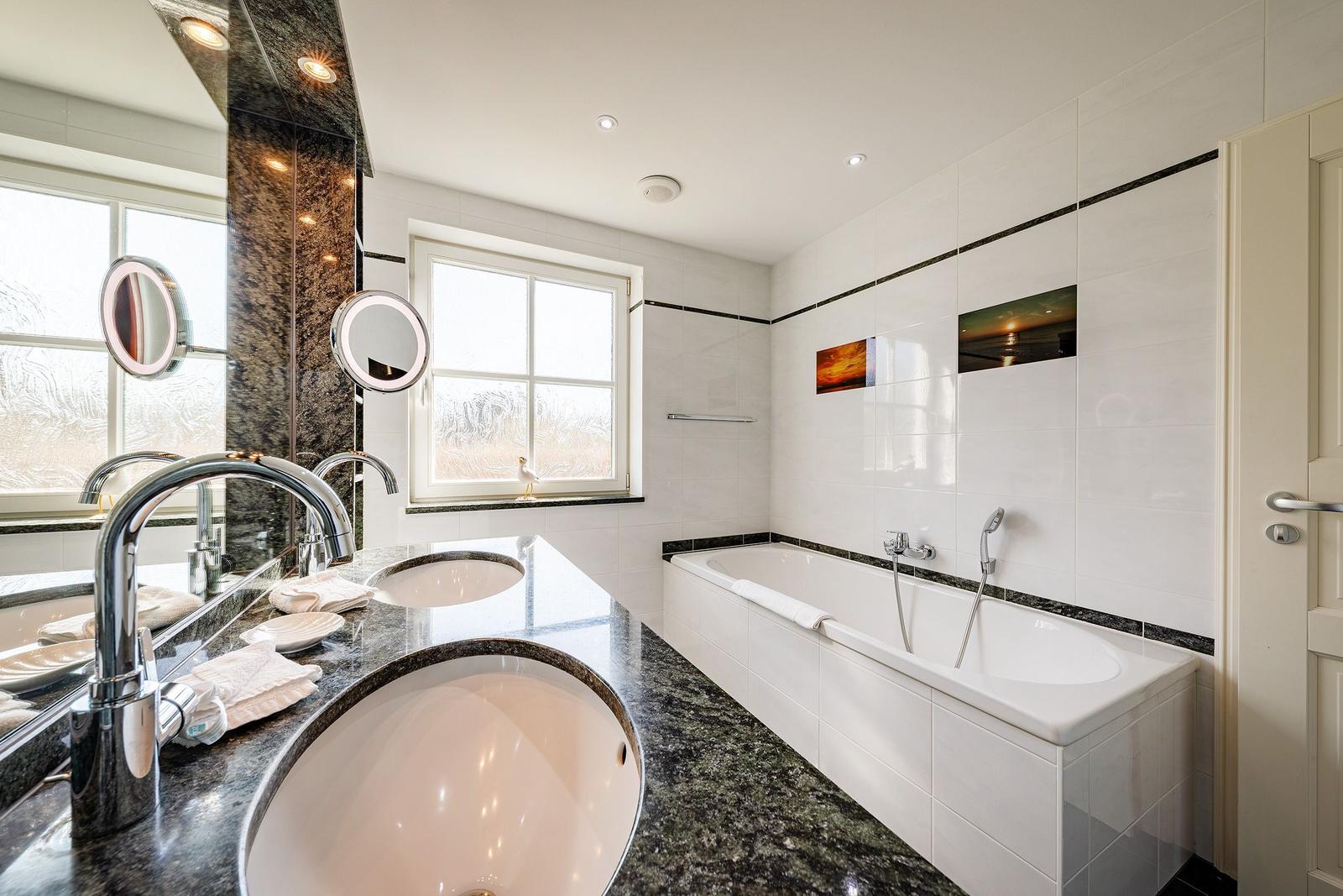 Badezimmer mit Badewanne, Waschtisch und Fenster