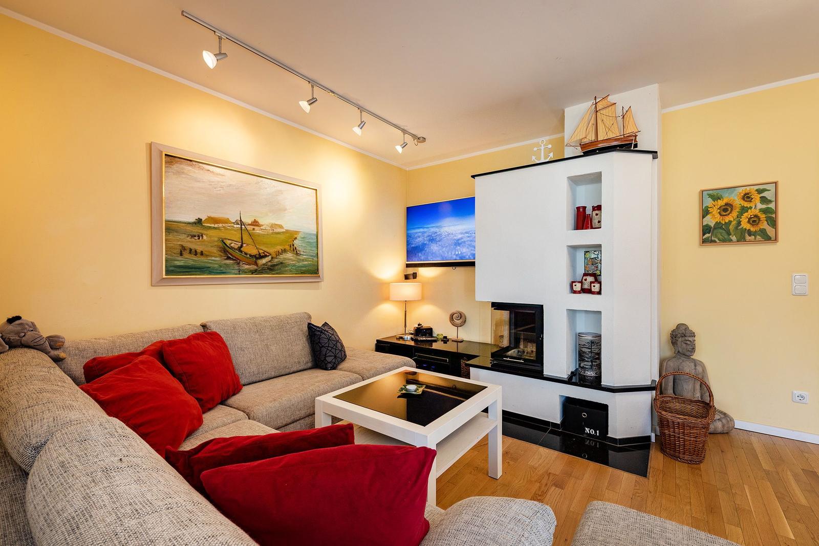 Wohnzimmer mit Sofa, Fernseher und Kamin. Wandbilder und Dekorationen.