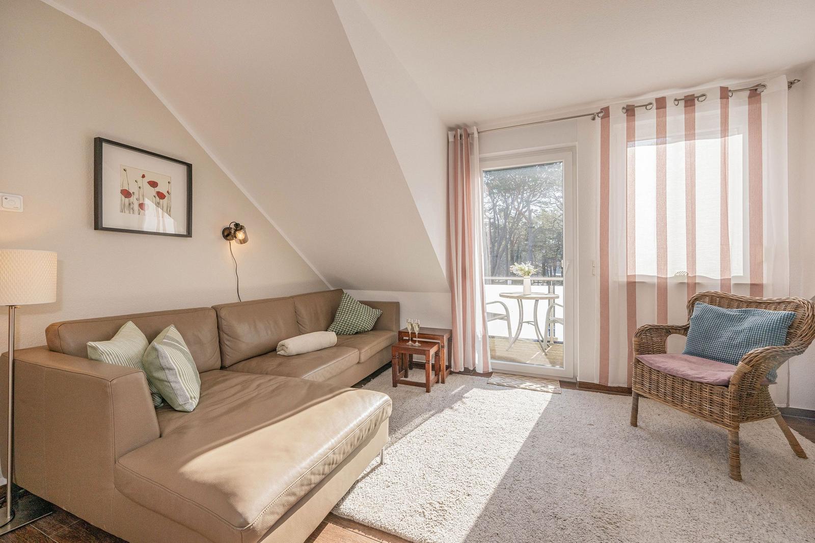 Wohnzimmer mit Sofa, Sessel und Balkonansicht