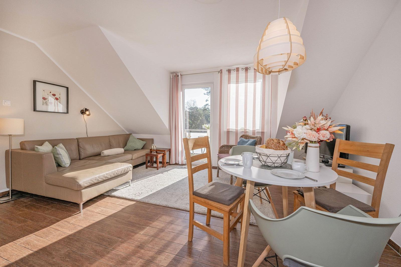 Wohn- und Essbereich mit Sofa, Tisch und Stühlen unter schrägen Decken.