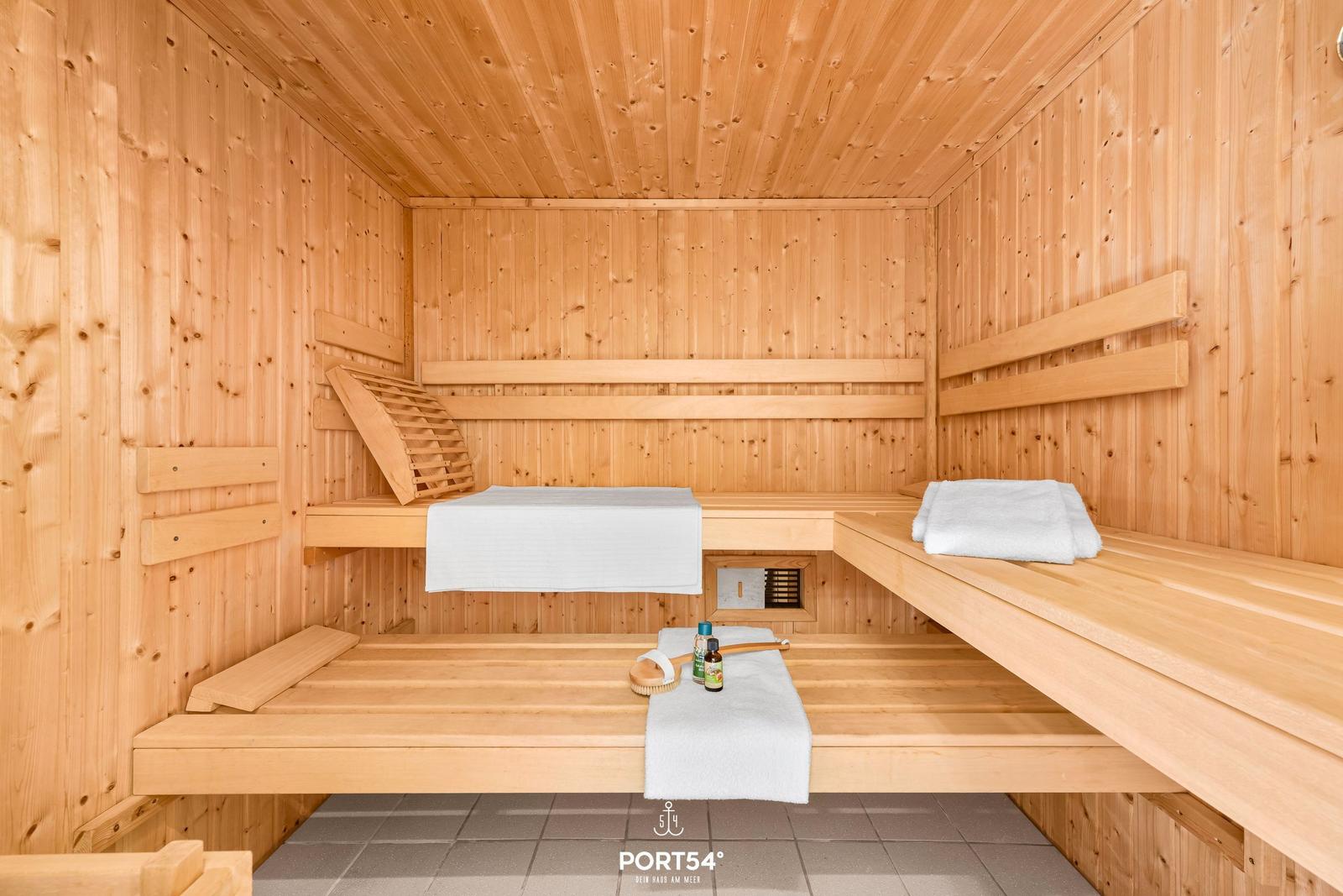 Holzsauna mit Bänken, Handtüchern und Saunakissen.