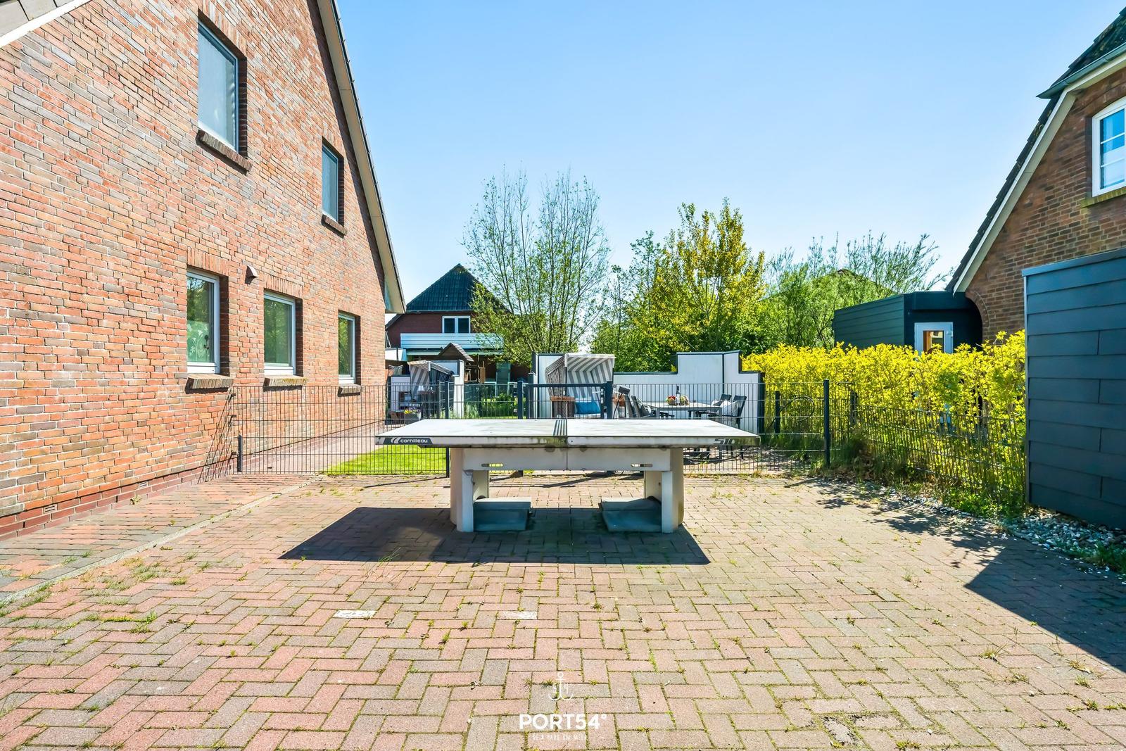 Hinterhof mit Tischtennisplatte, Grillbereich und Sitzgelegenheiten.