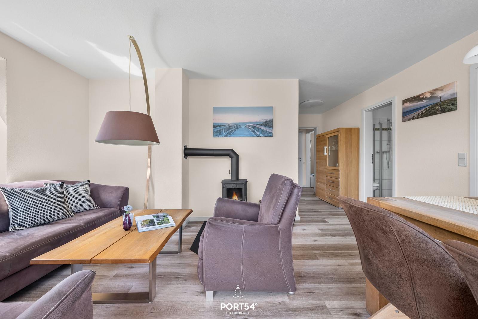 Wohnzimmer mit Sofa, Sessel, Kamin und Essbereich. Holzfußboden und Wandbilder.