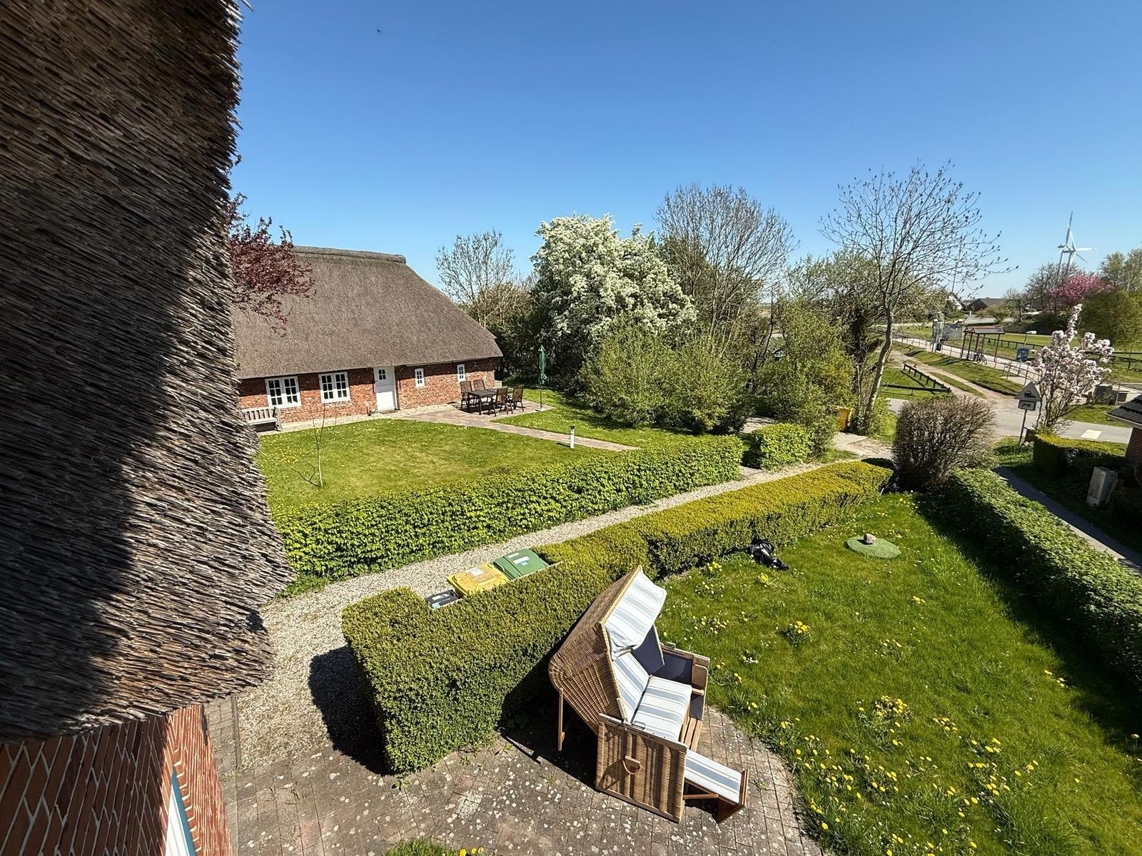 Dorfhaus mit Dachstuhl, Garten und Sonnenliege. Blick auf den Hof und umliegende Bäume.