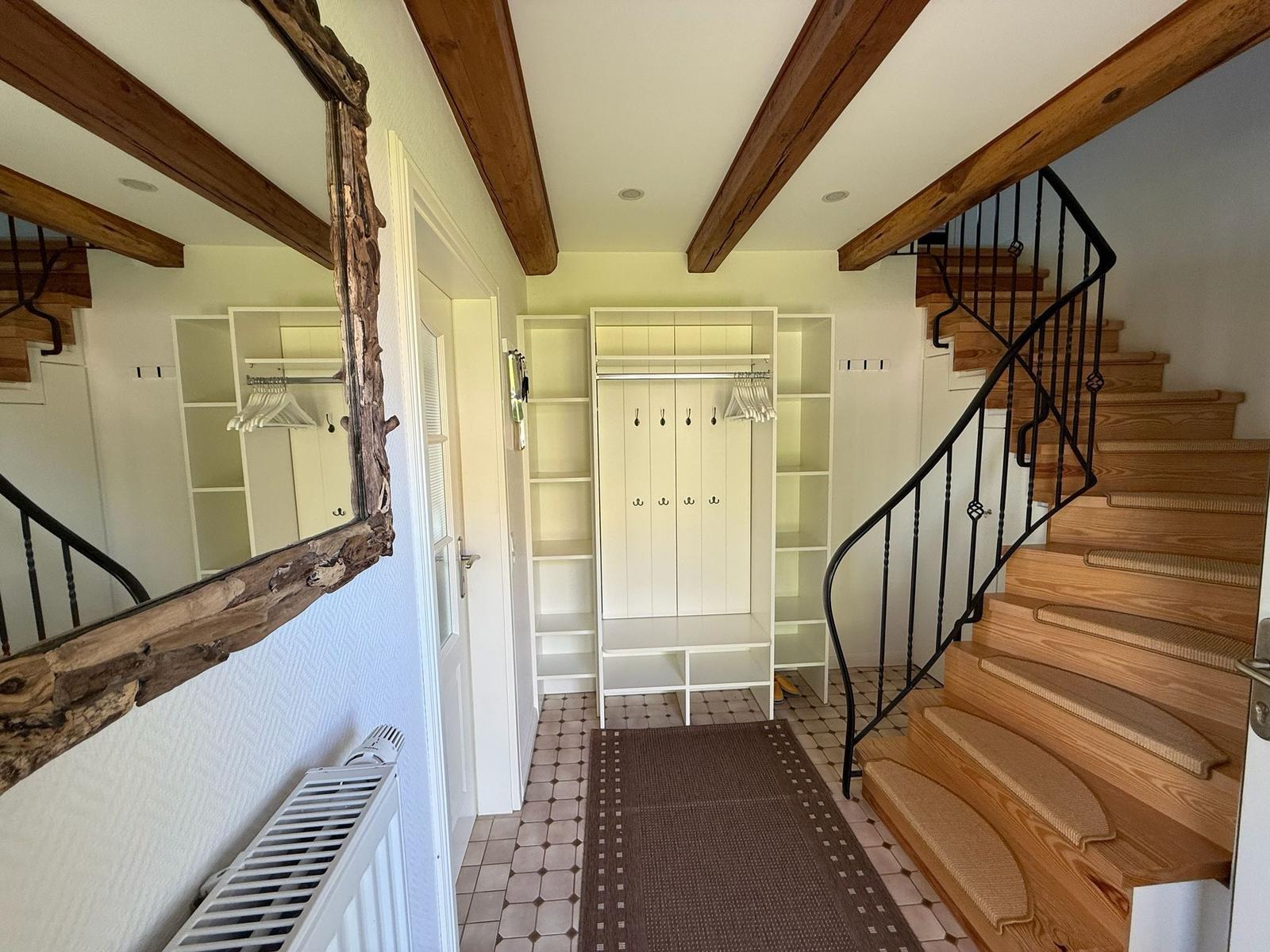 Eingangsbereich mit Garderobe, Treppe und Spiegel mit rustikalem Rahmen.