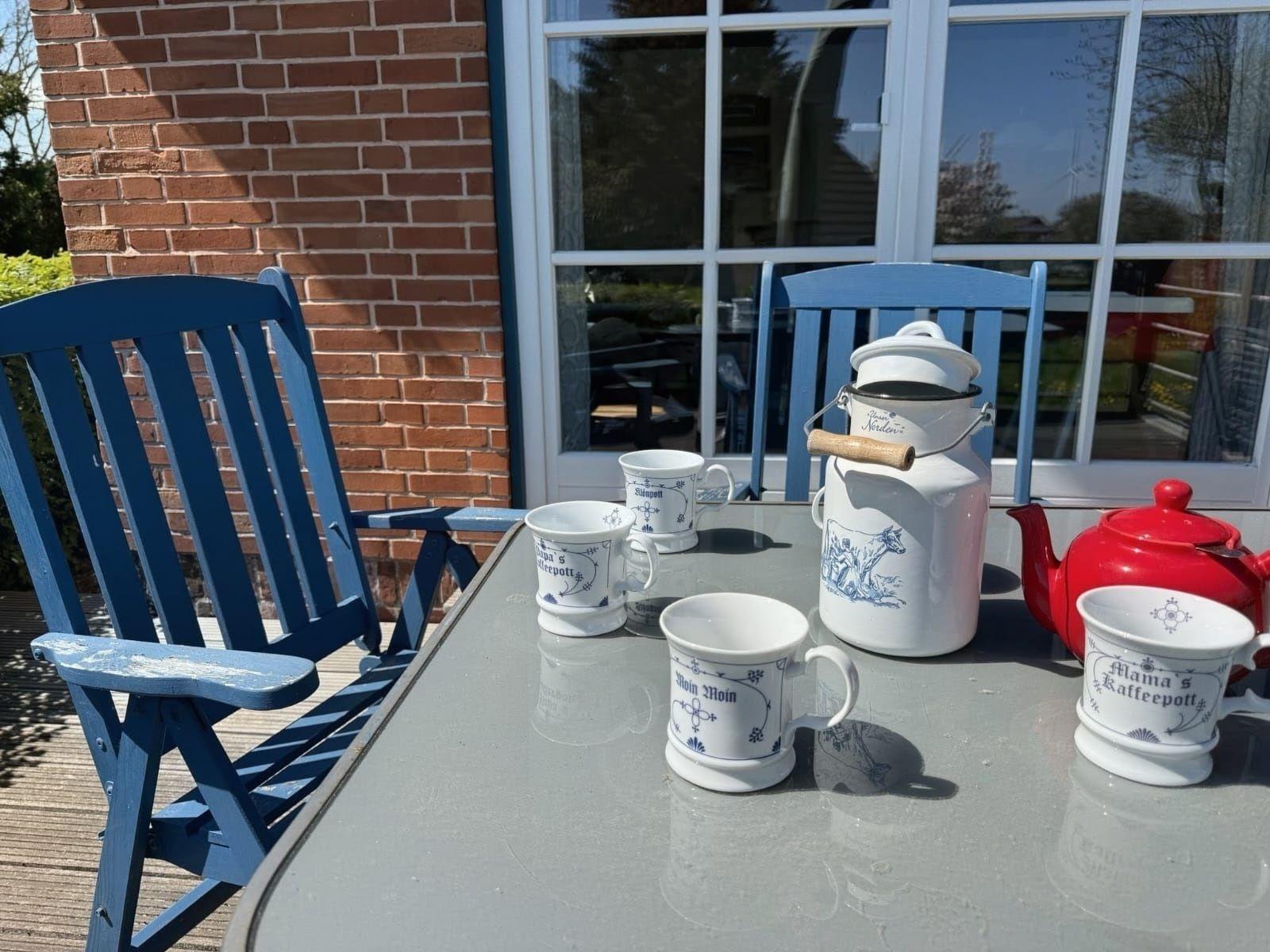 Außenbereich mit Tisch, Stühlen und Kaffeeware.