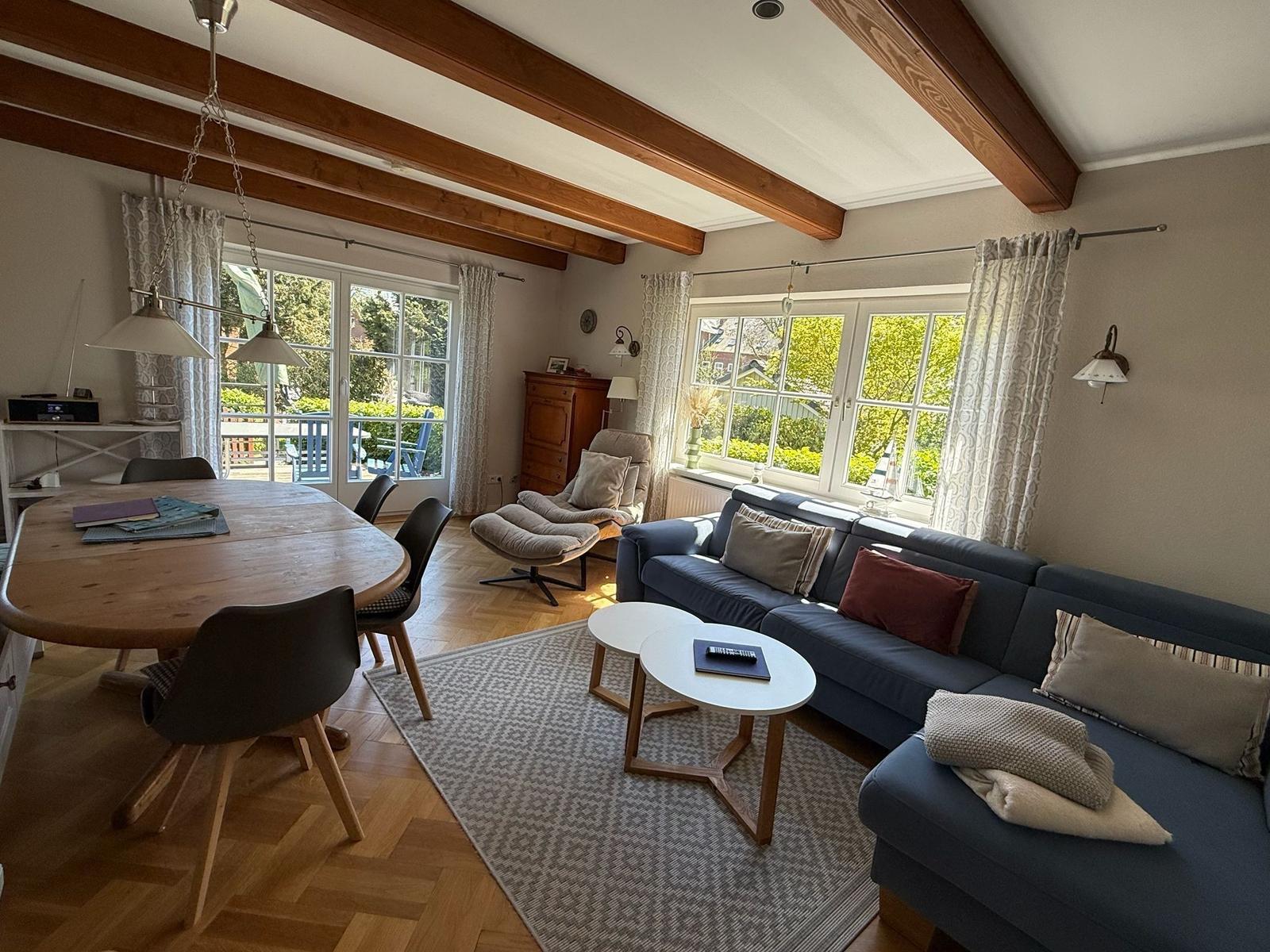 Wohn- und Essbereich mit Holzbalken, Sofa, Esstisch und Fenster zur Terrasse.