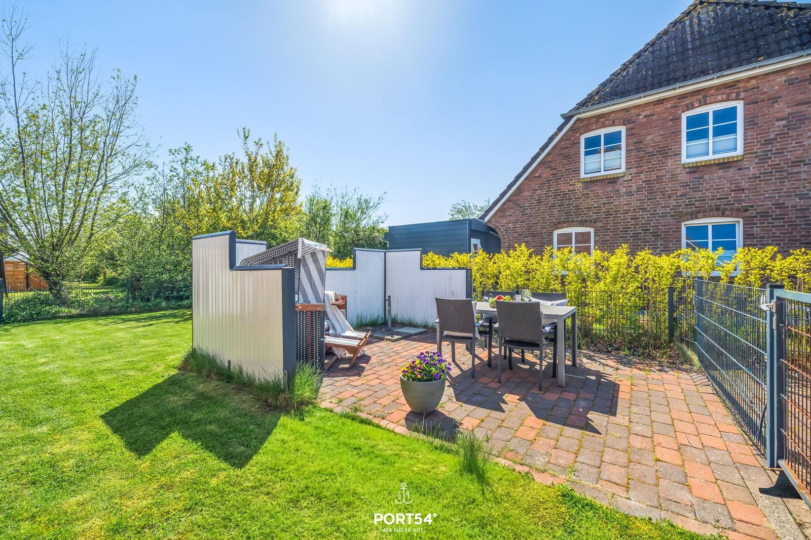 Hinterhof mit Grillplatz, Sitzgelegenheiten und grünem Rasenbereich.