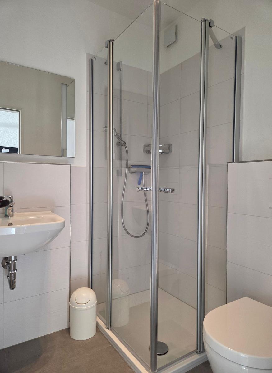 Badezimmer mit Dusche, Waschbecken und Toilette.