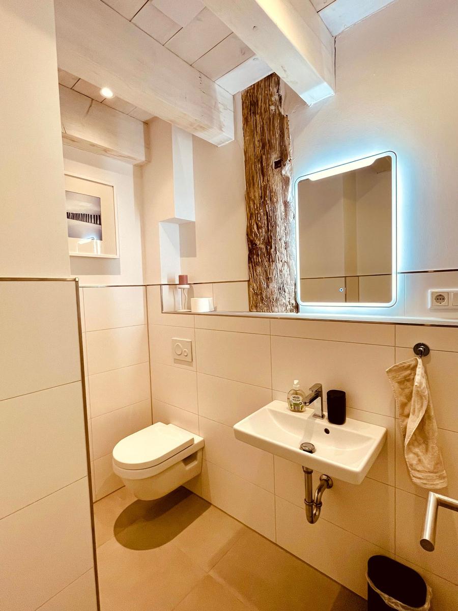 Bathroom with toilet, sink, and lit mirror