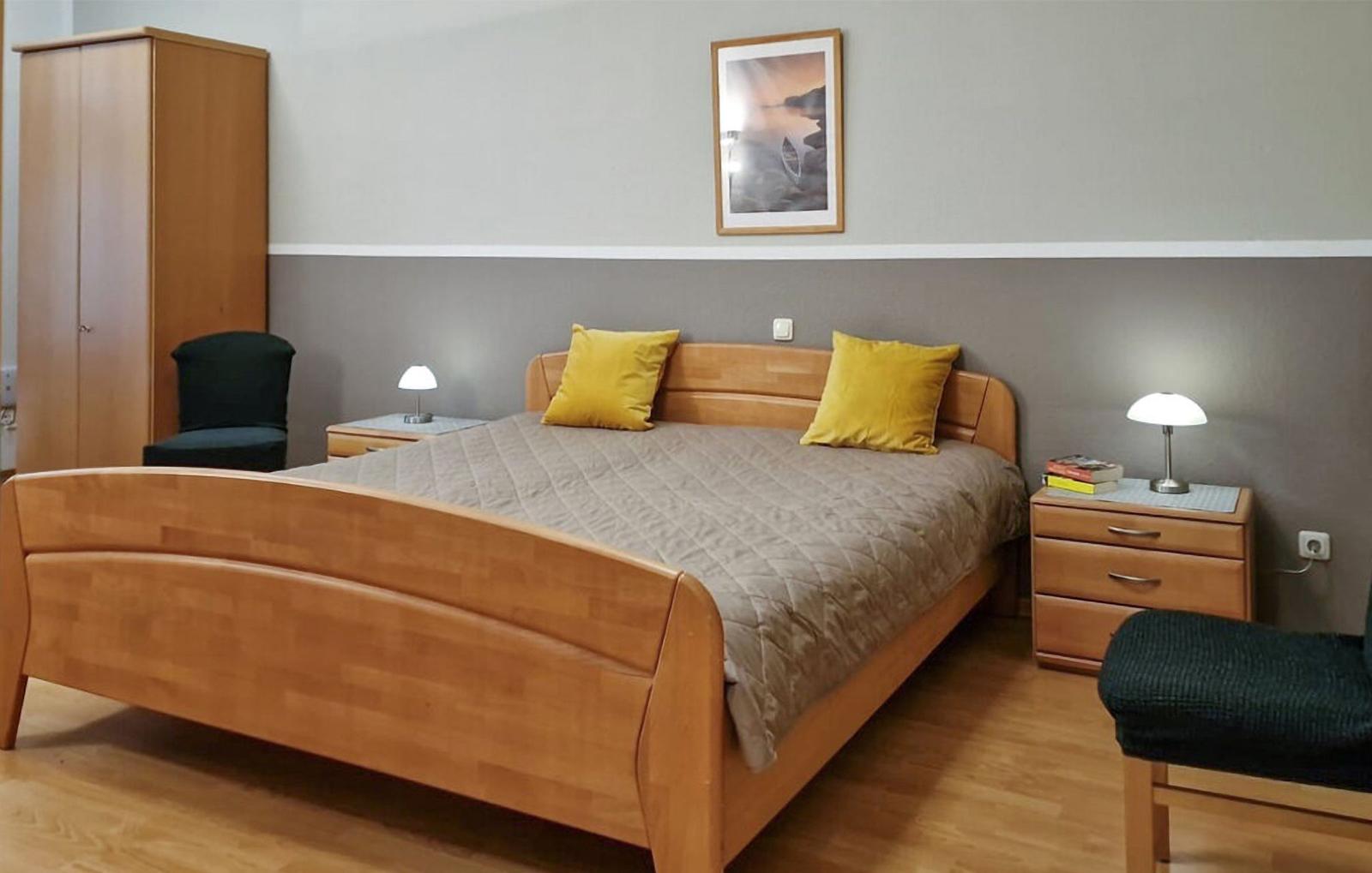 Schlafzimmer mit Holzbett, zwei Nachttischen und Kleiderschrank.