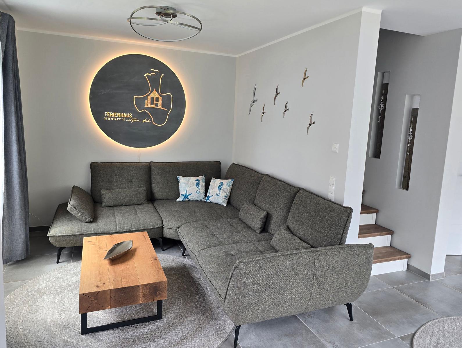 Wohnzimmer mit grauem Sofa, Holztisch und Wanddekoration.