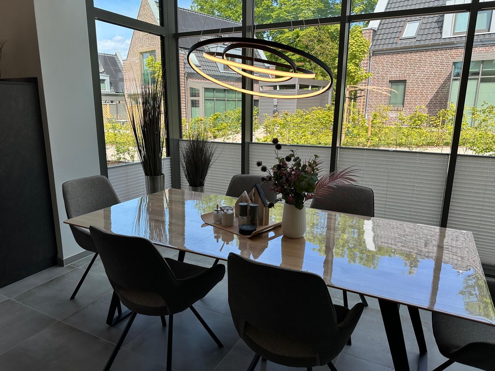 Esszimmer mit Tisch, Stühlen und großem Fensterblick auf Garten