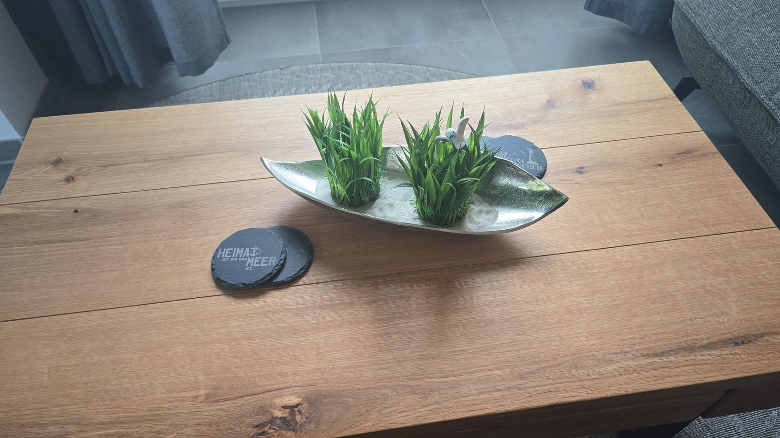 Holztisch mit Pflanzenarrangement und Steinuntersetzer