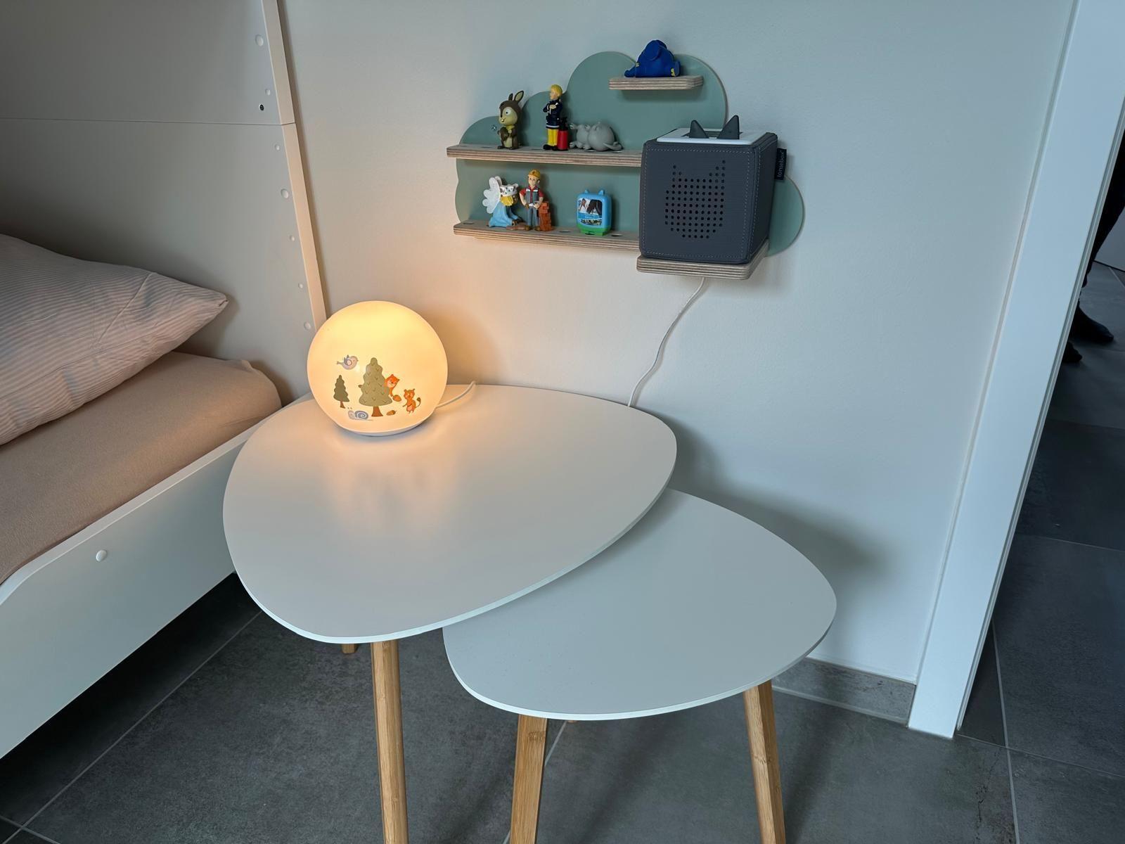 Schreibtisch mit Lampe und Regal an Wand, daneben Bett