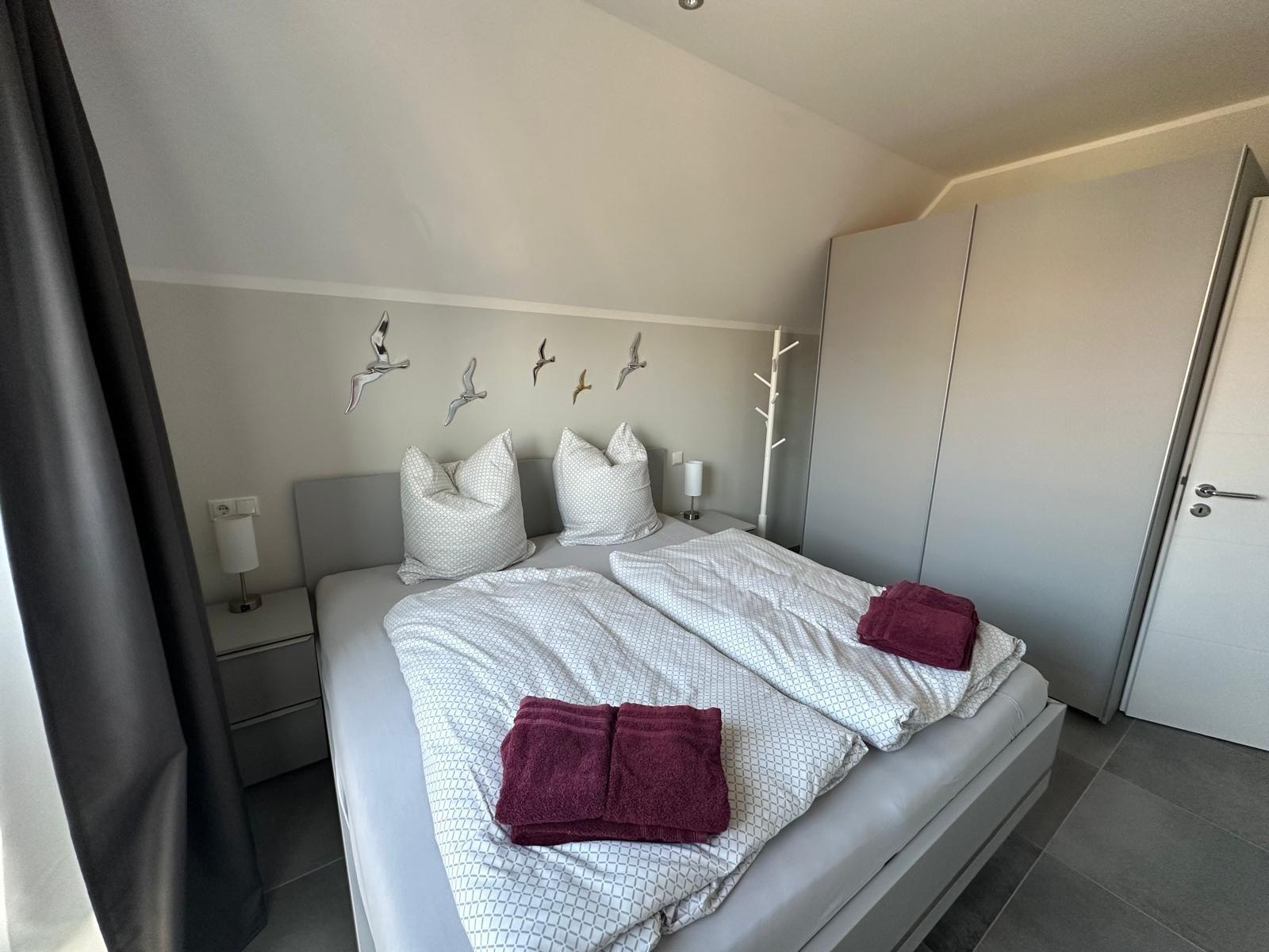 Schlafzimmer mit Doppelbett, Nachttischen und Kleiderschrank. Auf dem Bett liegen Handtücher.