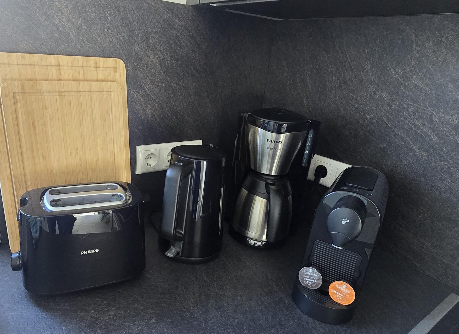 Küchenbereich mit Toaster, Kaffeemaschine und Wasserkocher auf dunkler Arbeitsfläche.