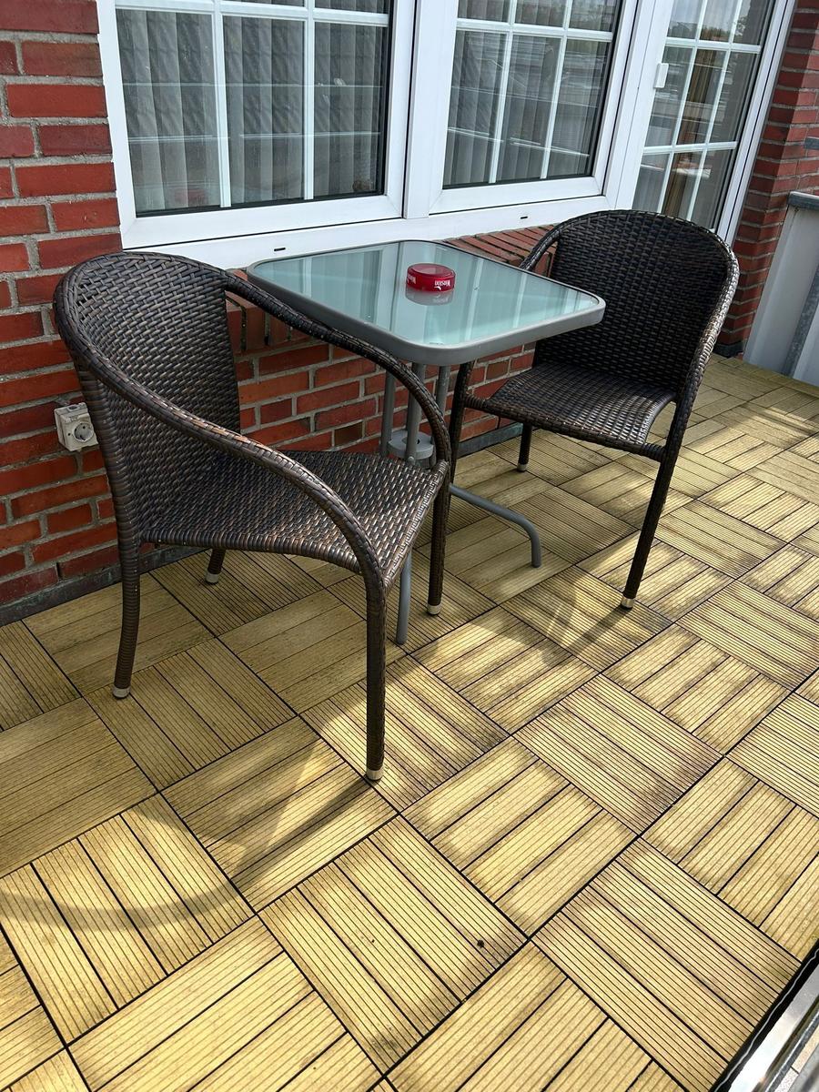 Terrasse mit zwei Stühlen und Tisch vor Fenster mit rotem Backsteinmauerwerk