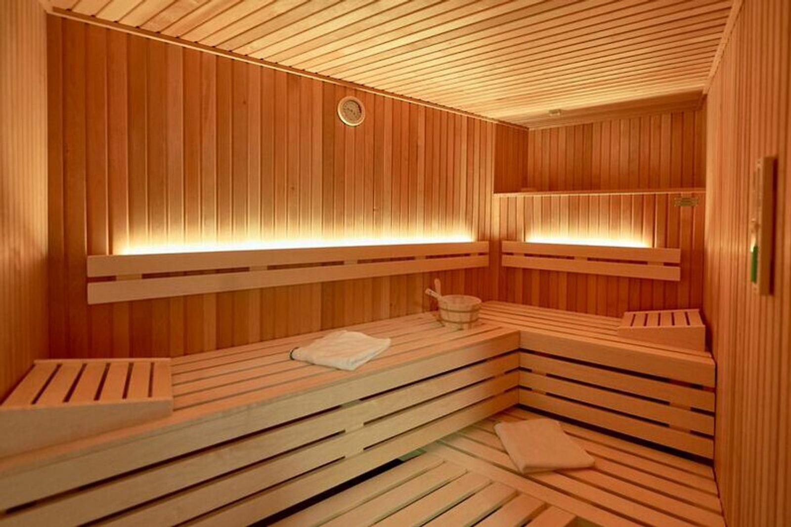 Sauna mit Holzbank, Thermometer und Badematten.
