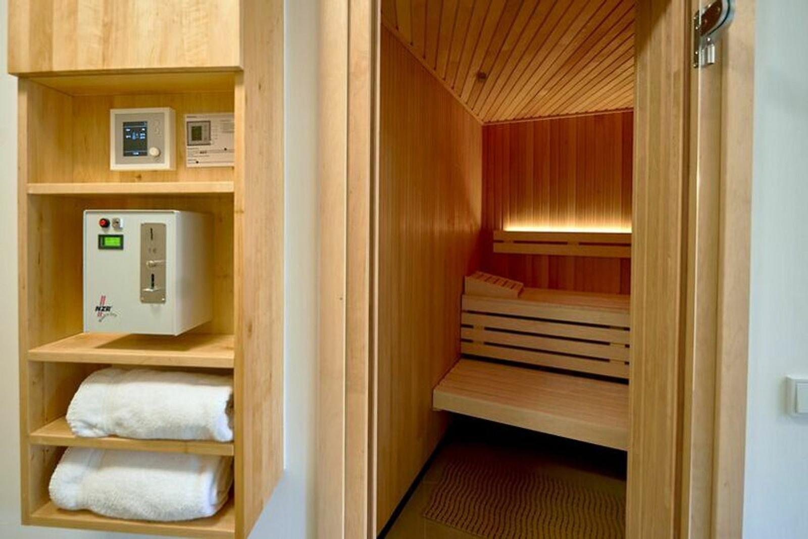 Sauna mit Holzbank und Heizgerät. Handtuchhalter und Handtücher.