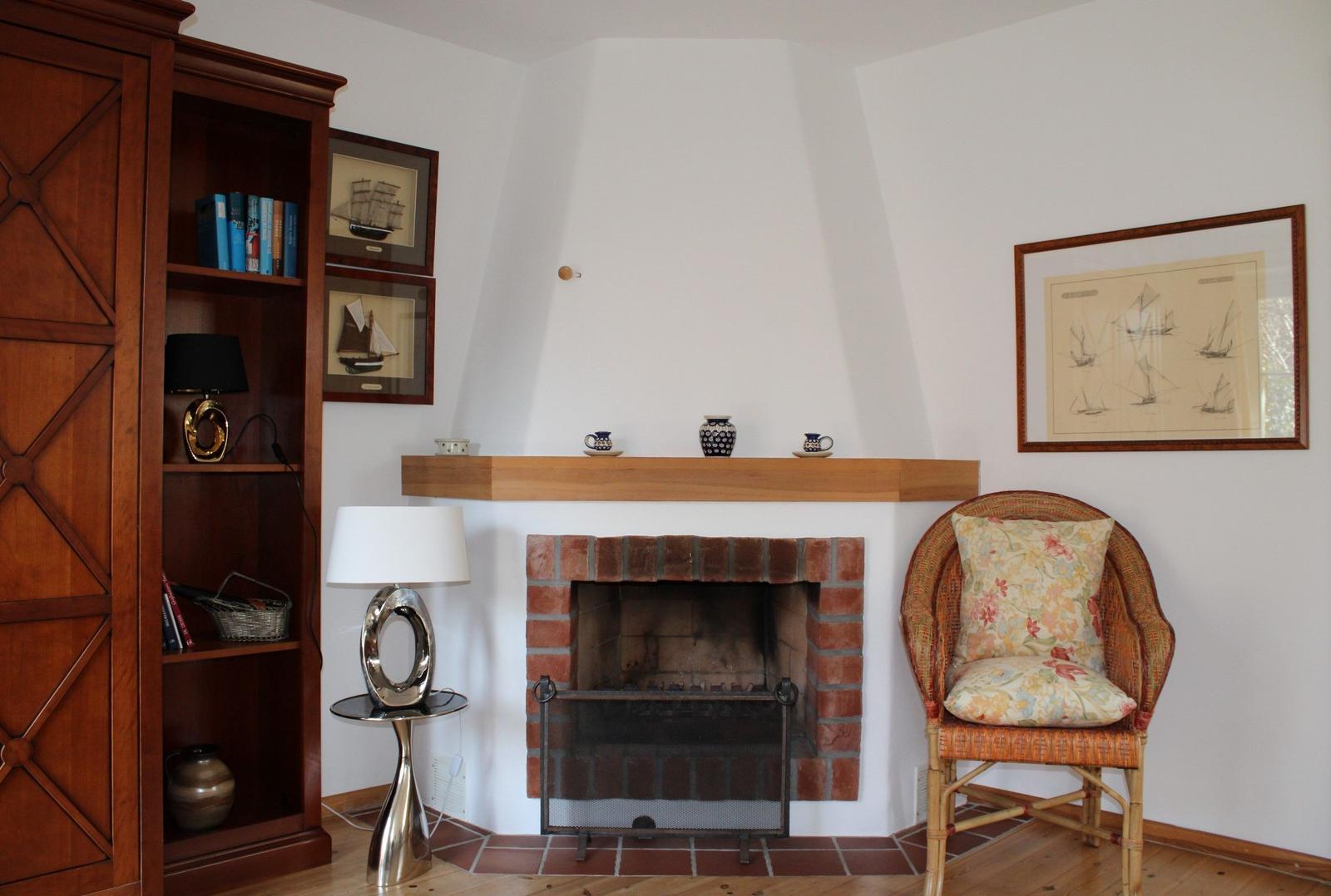 Raum mit Kamin, Bücherregal, Stuhl und Wandbildern mit Schiffen.
