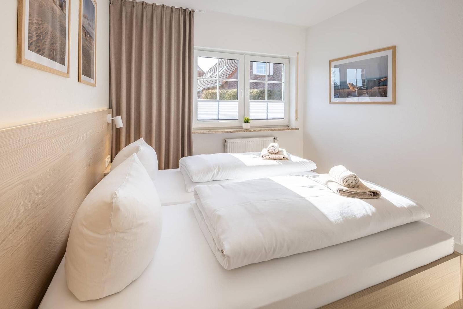 Schlafzimmer mit Doppelbett, Fenster und Bildern an den Wänden.