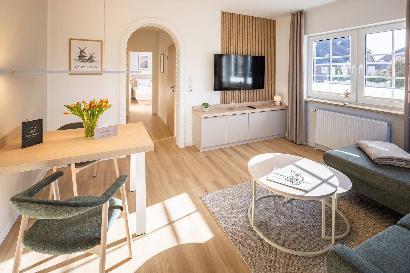 Wohnzimmer mit Essbereich, TV und Blick aufs Zimmer.