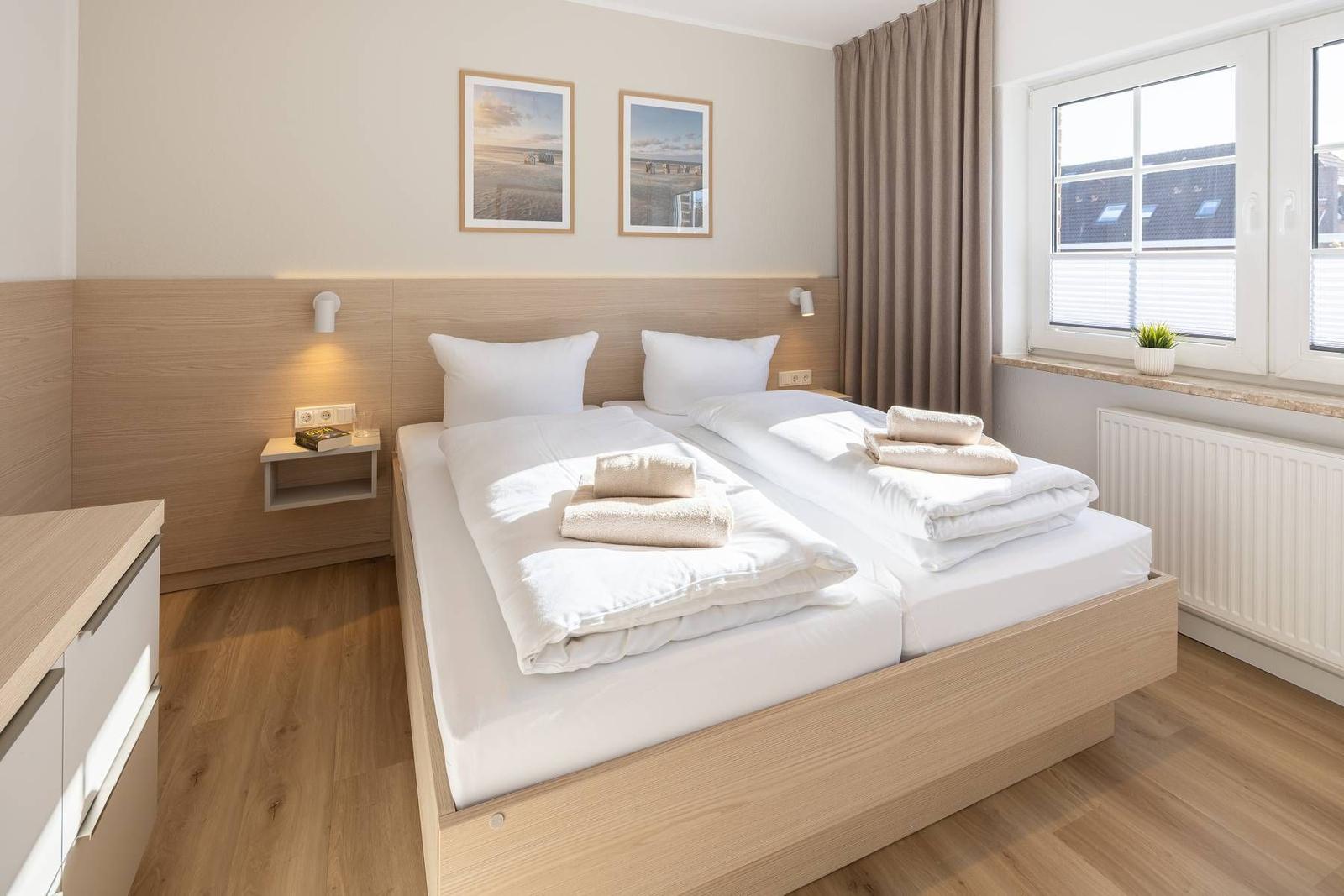 Schlafzimmer mit Doppelbett, Holzmöbeln und Fenster mit Blick.