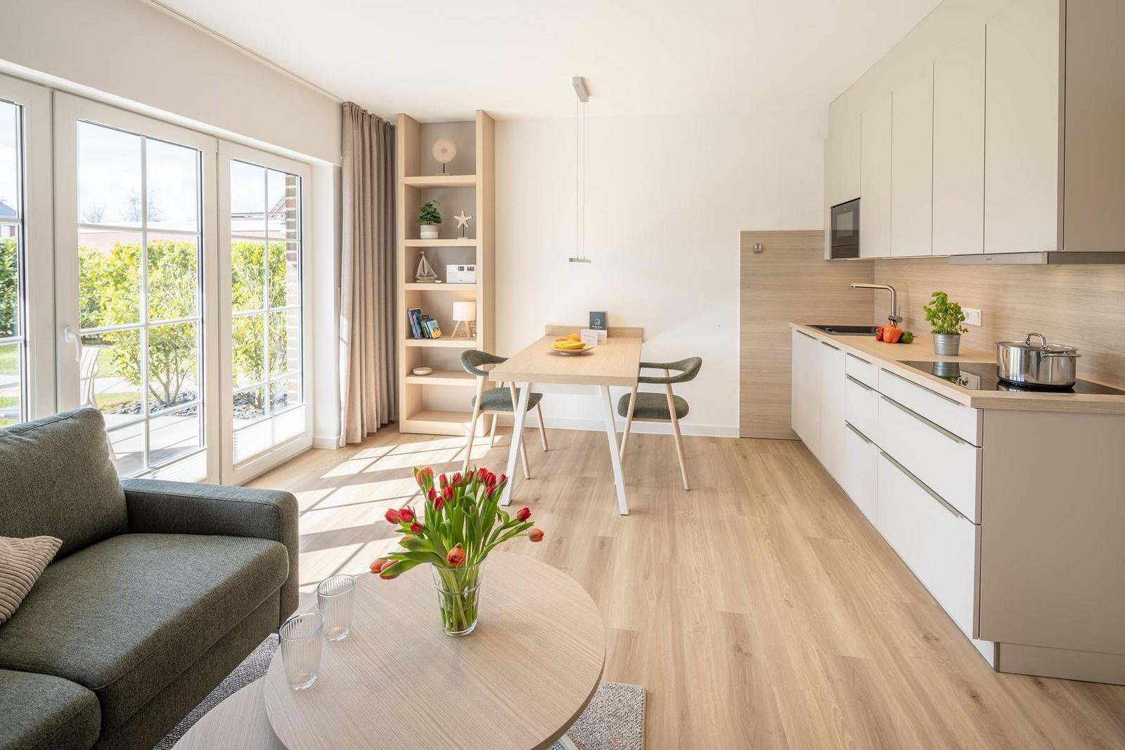 Wohnung mit Küche, Esstisch und Sofa. Durchgangstür zum Garten.