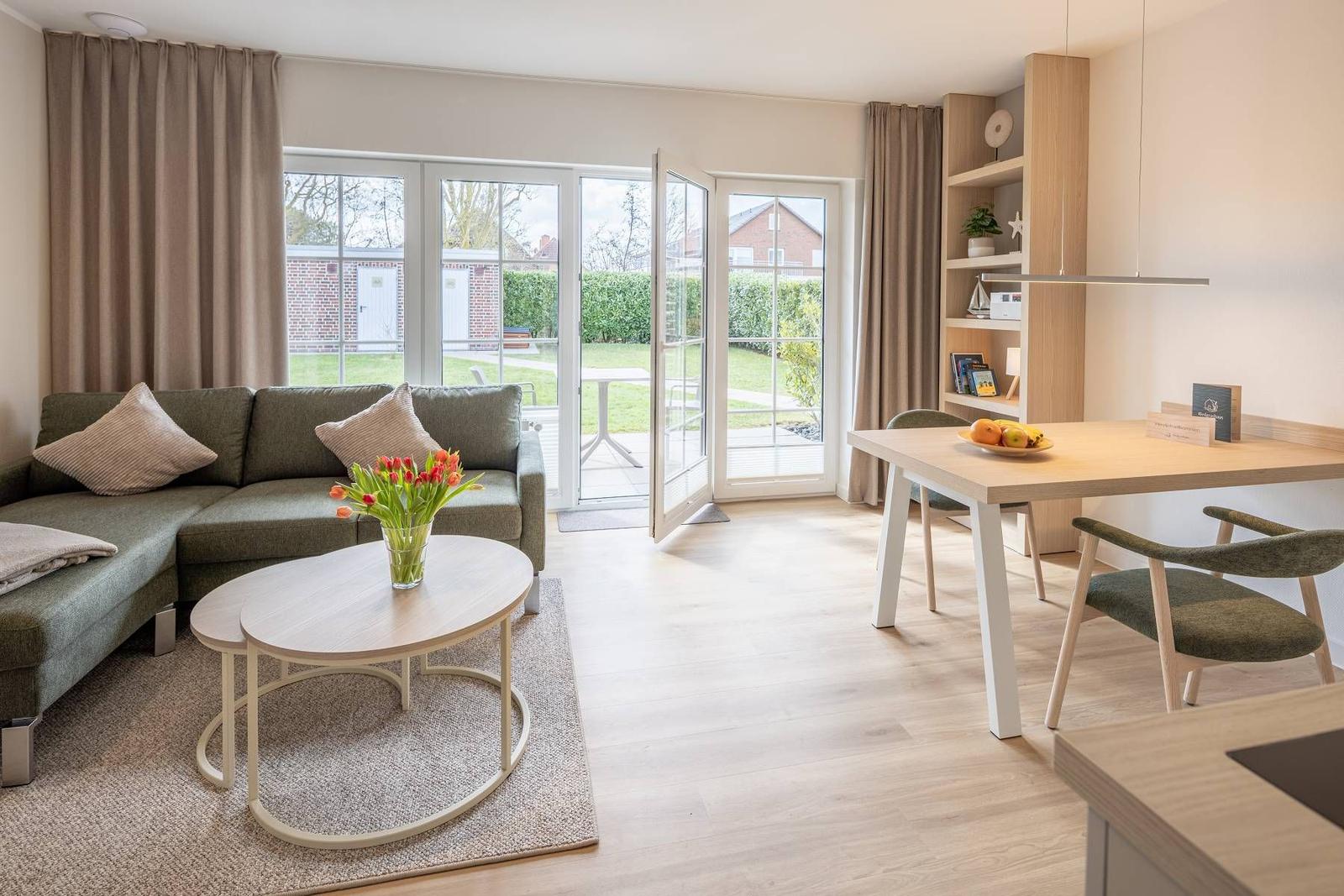 Wohn- und Essbereich mit Sofa, Tisch und Blick auf den Garten.