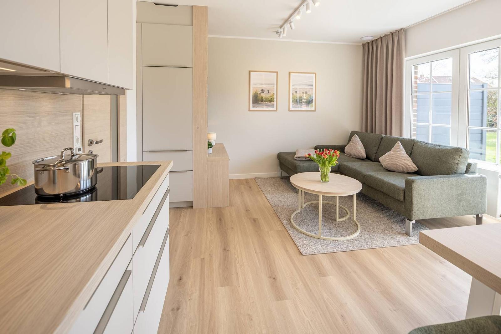 Moderne Küche und Wohnbereich mit Sofa, Tisch und Fenster.