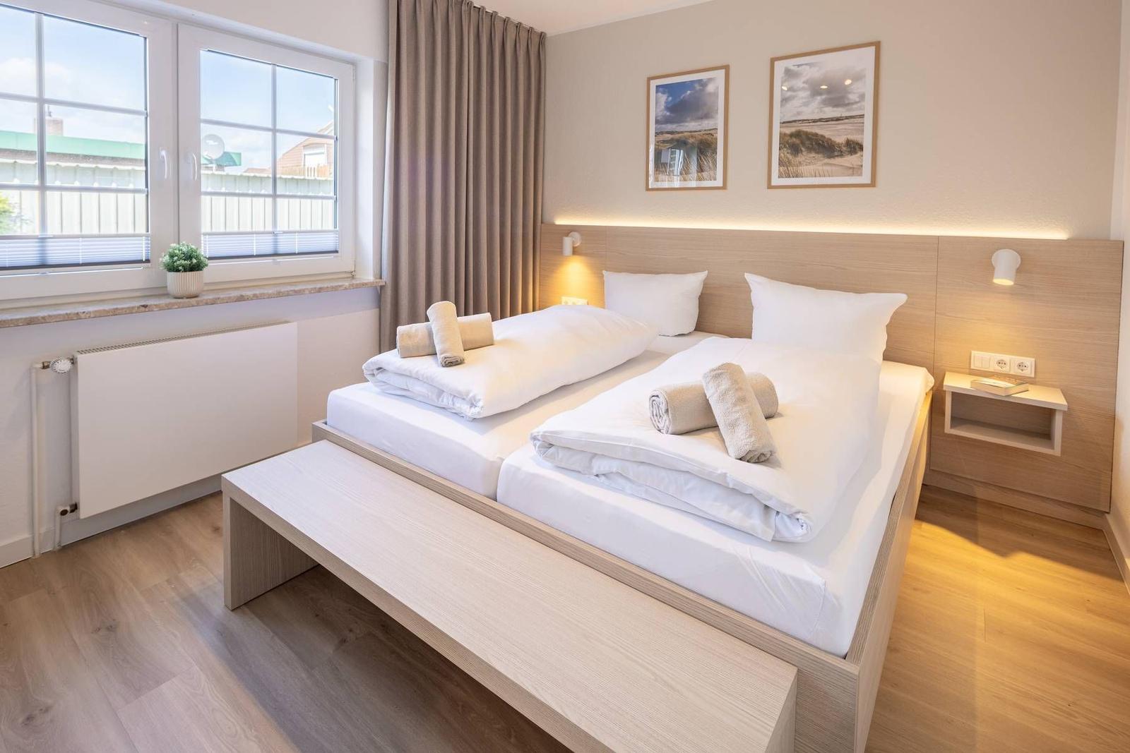Schlafzimmer mit Doppelbett, Fenster und Holzboden.