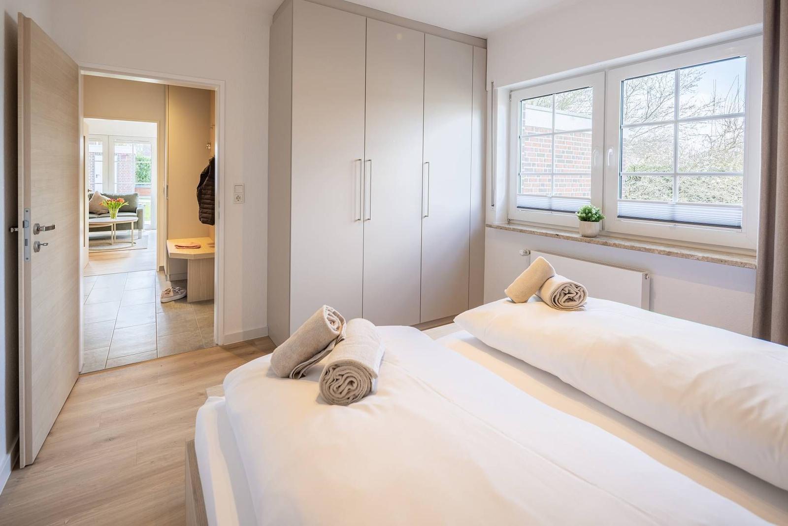 Schlafzimmer mit Doppelbett, Kleiderschrank und Fenster. Durchgang zum Wohnbereich.